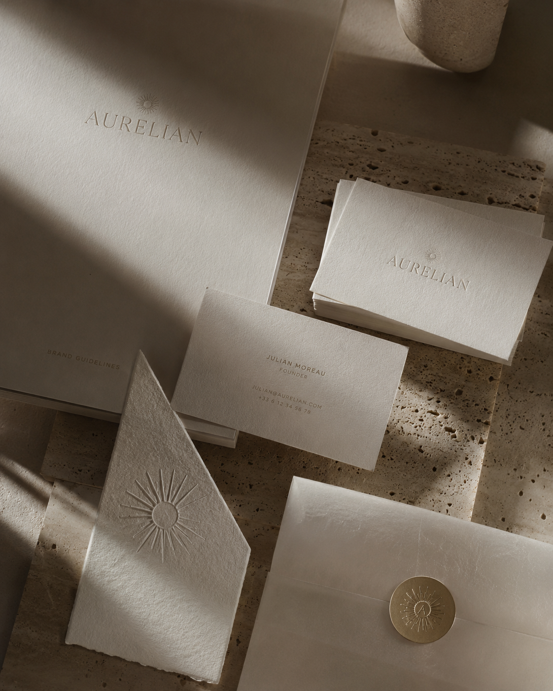 Aurelian brand identity — embossed stationery and wax seal on travertine in warm sunlight